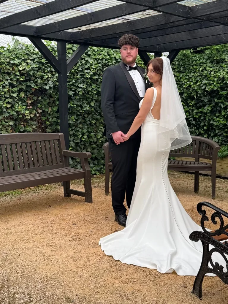 A newly married couple standing together in the garden