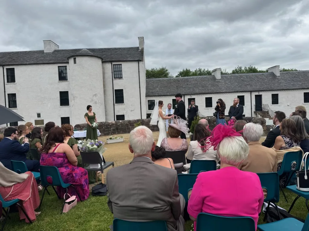 An outdoor wedding ceremony taking place in front of the historic building